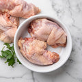 Raw pasture-raised chicken necks for dogs in a white bowl