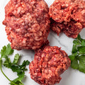 Portions of raw grass-fed ground beef for dogs with parsley on marble